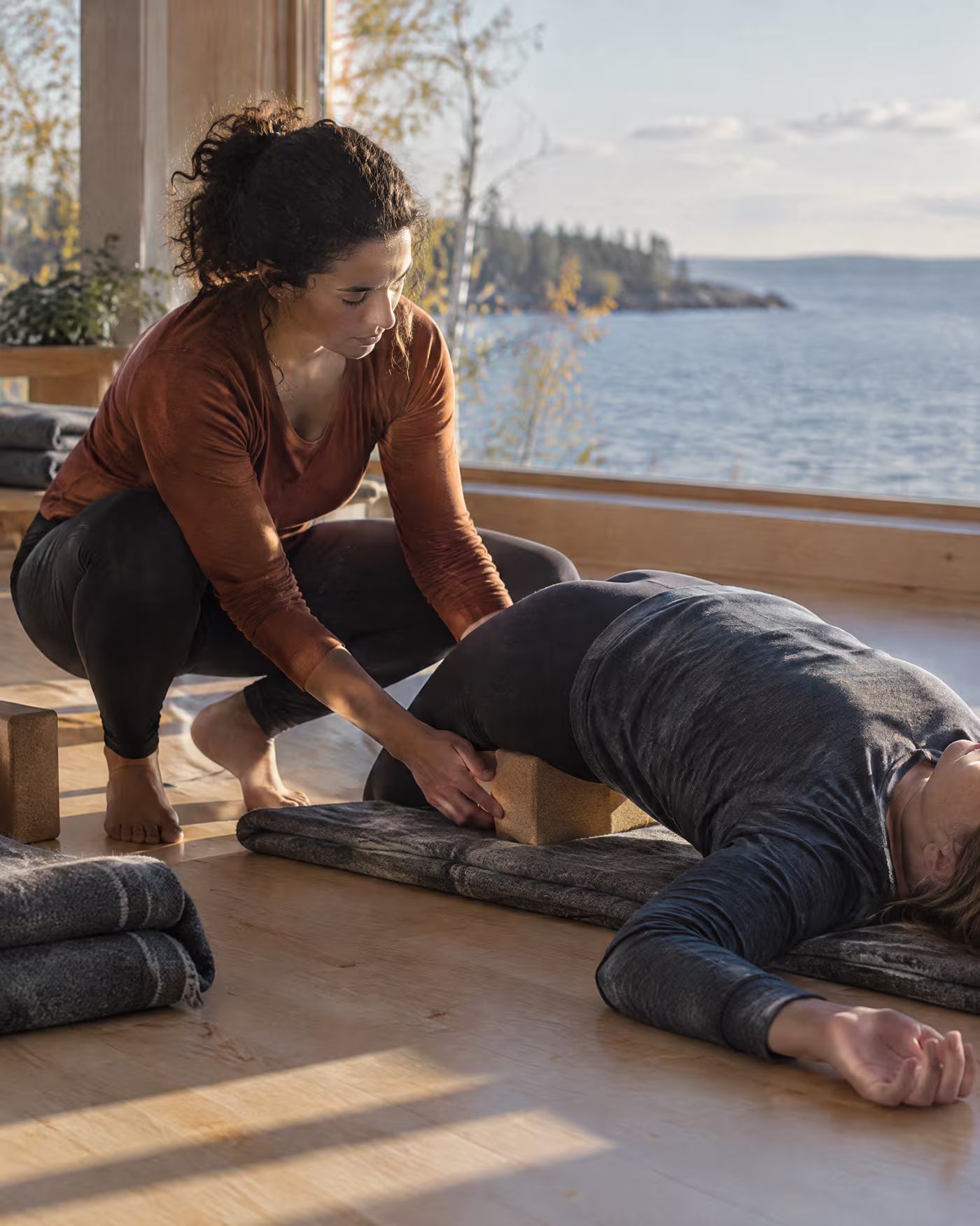 Claire sliding a cork block under a student's lower back in a supported bridge