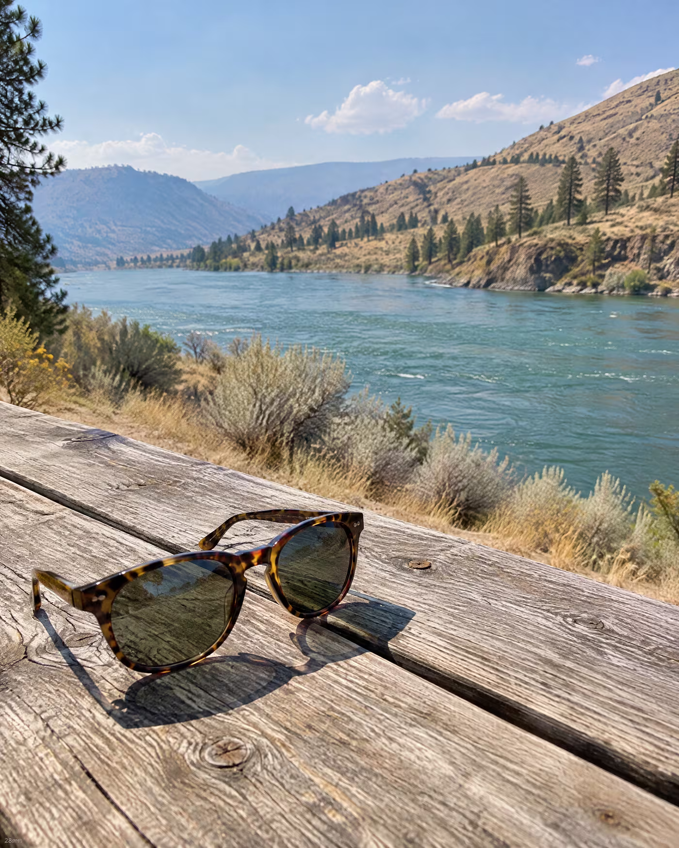 Tortoiseshell sunglasses on a picnic table above the Thompson River