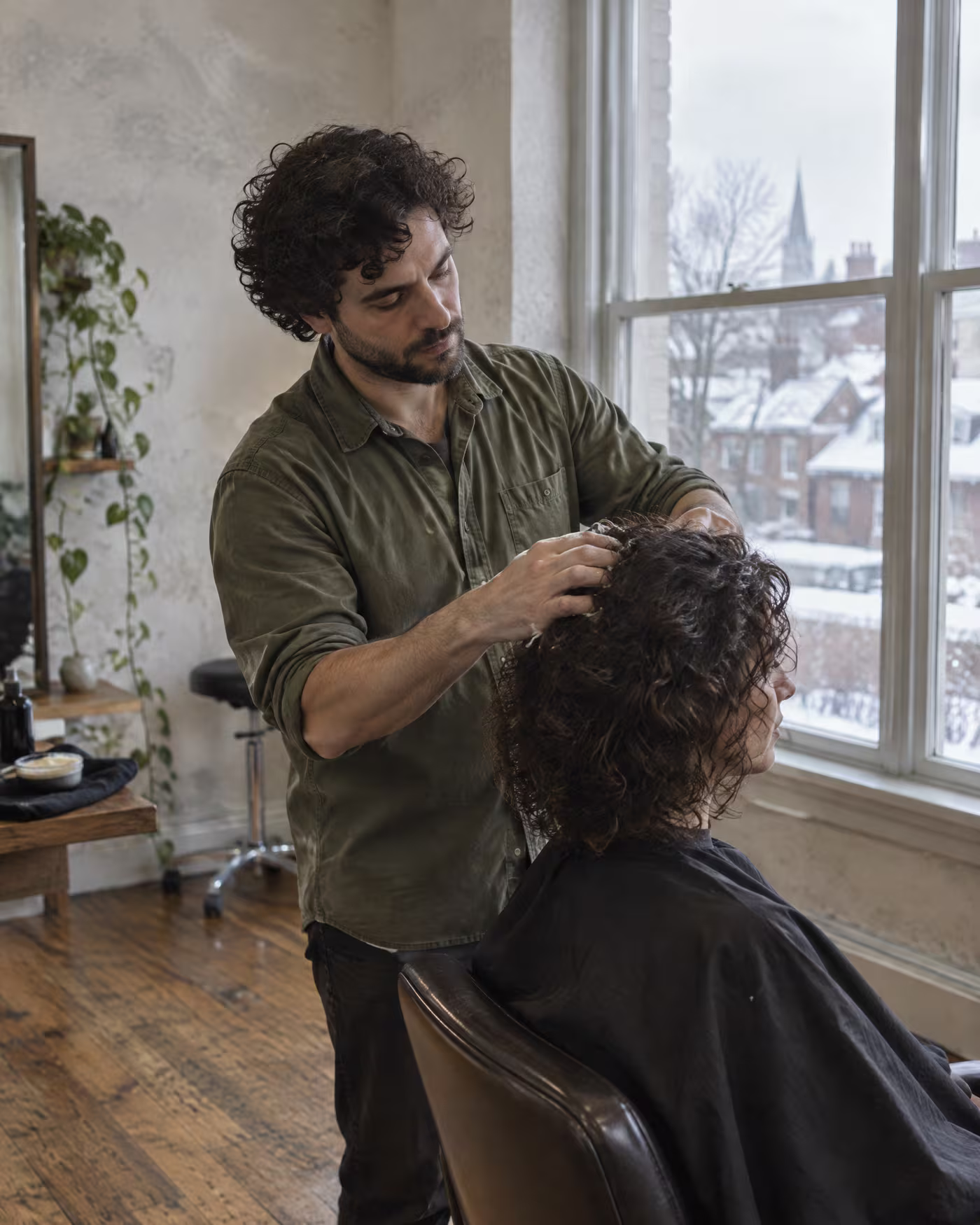 Mathieu working styling cream through a client's dark curls